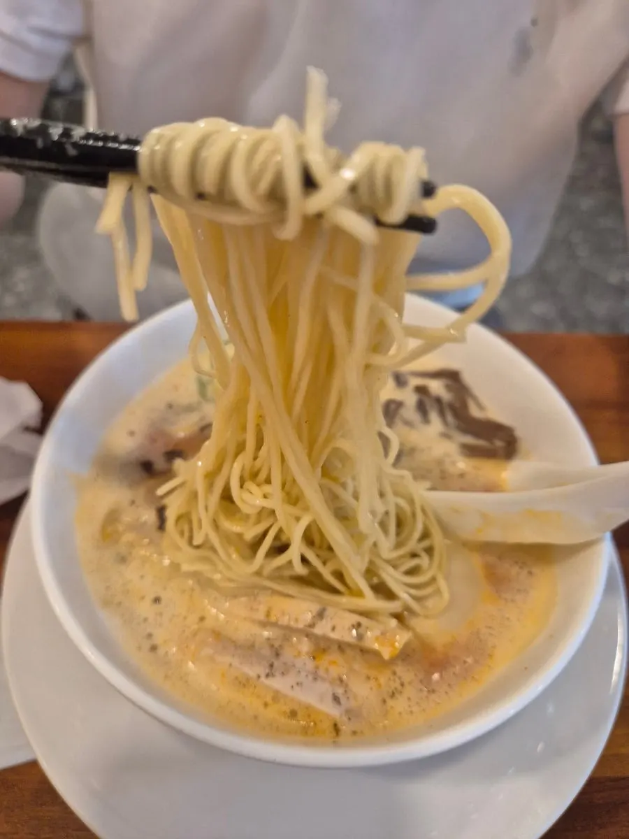 Thin Oreno Ramen noodles lifted with chopsticks