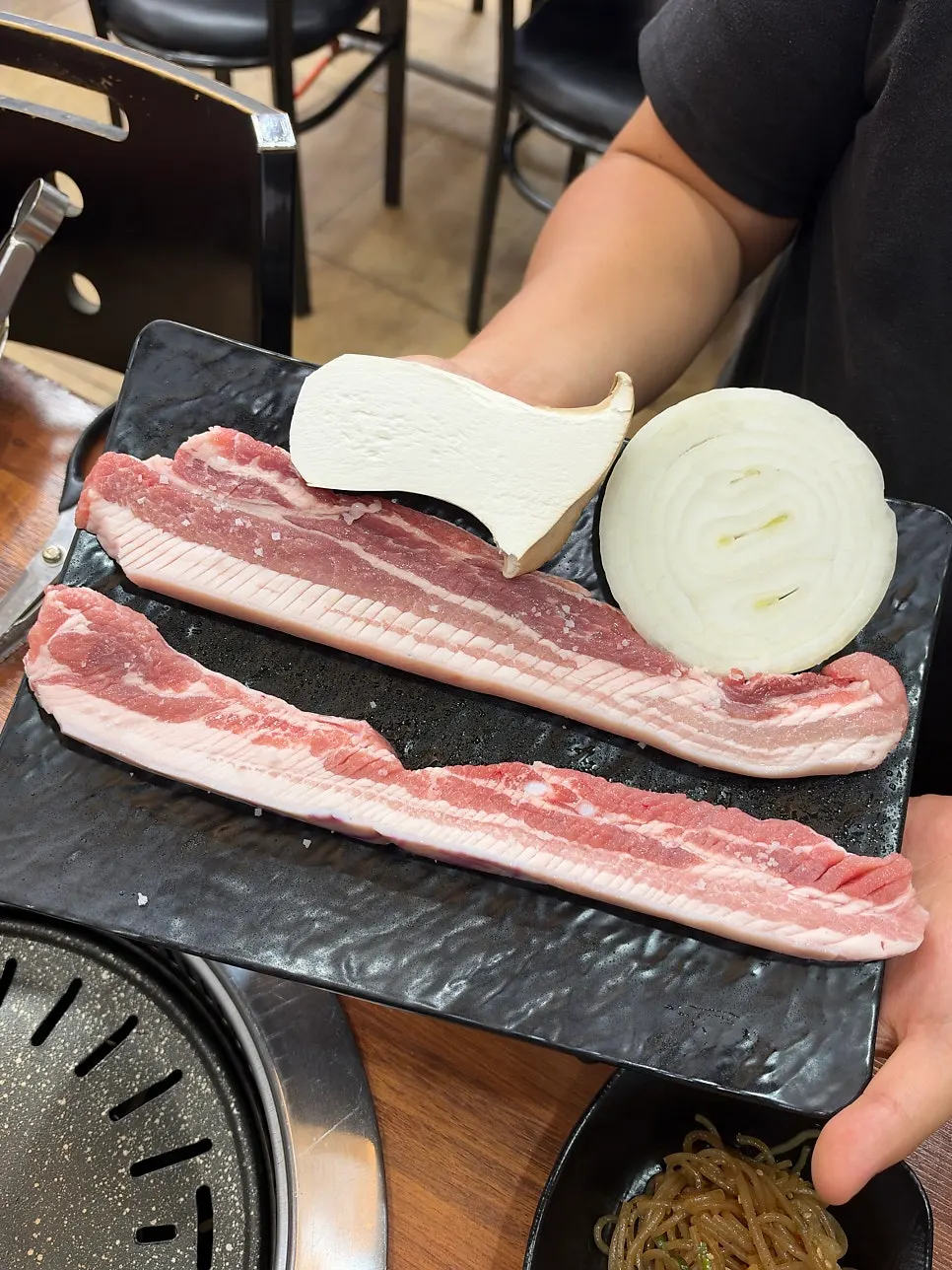 Scored black pork belly for two with onions and mushrooms