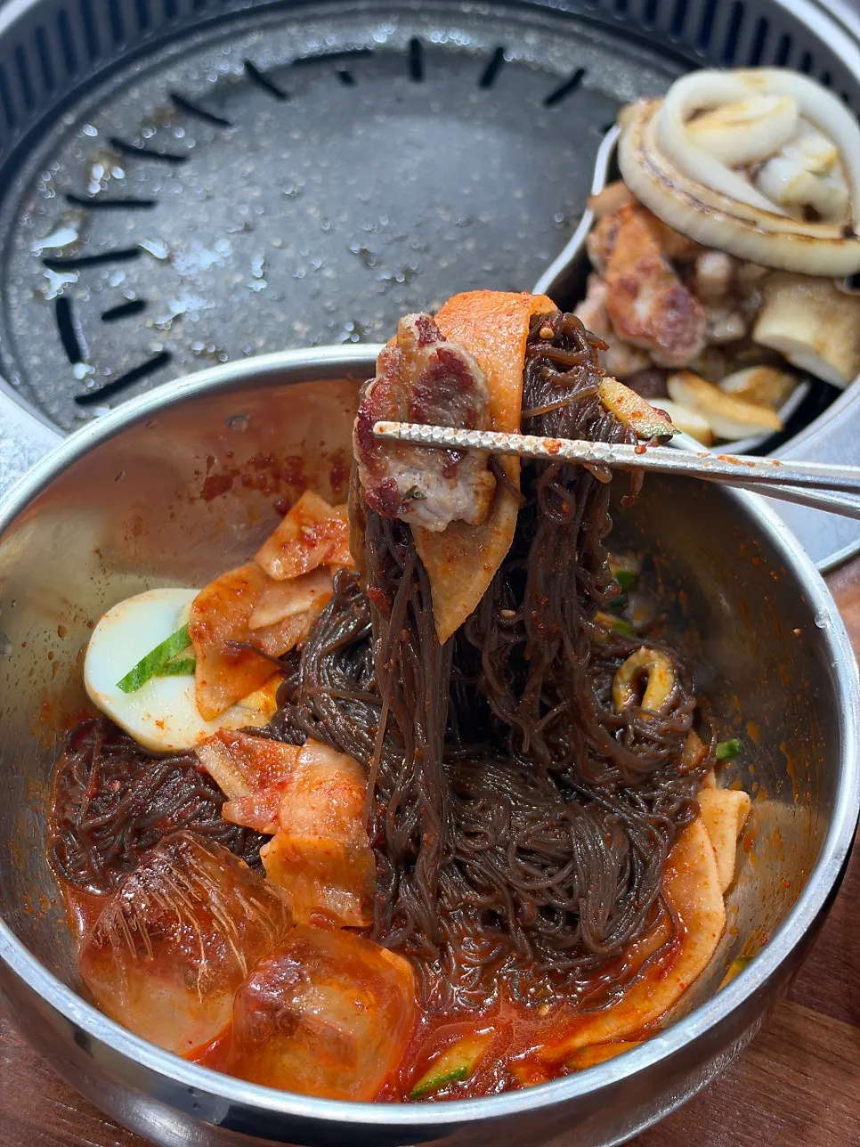 Tangy-spicy bibim naengmyeon noodles lifted up