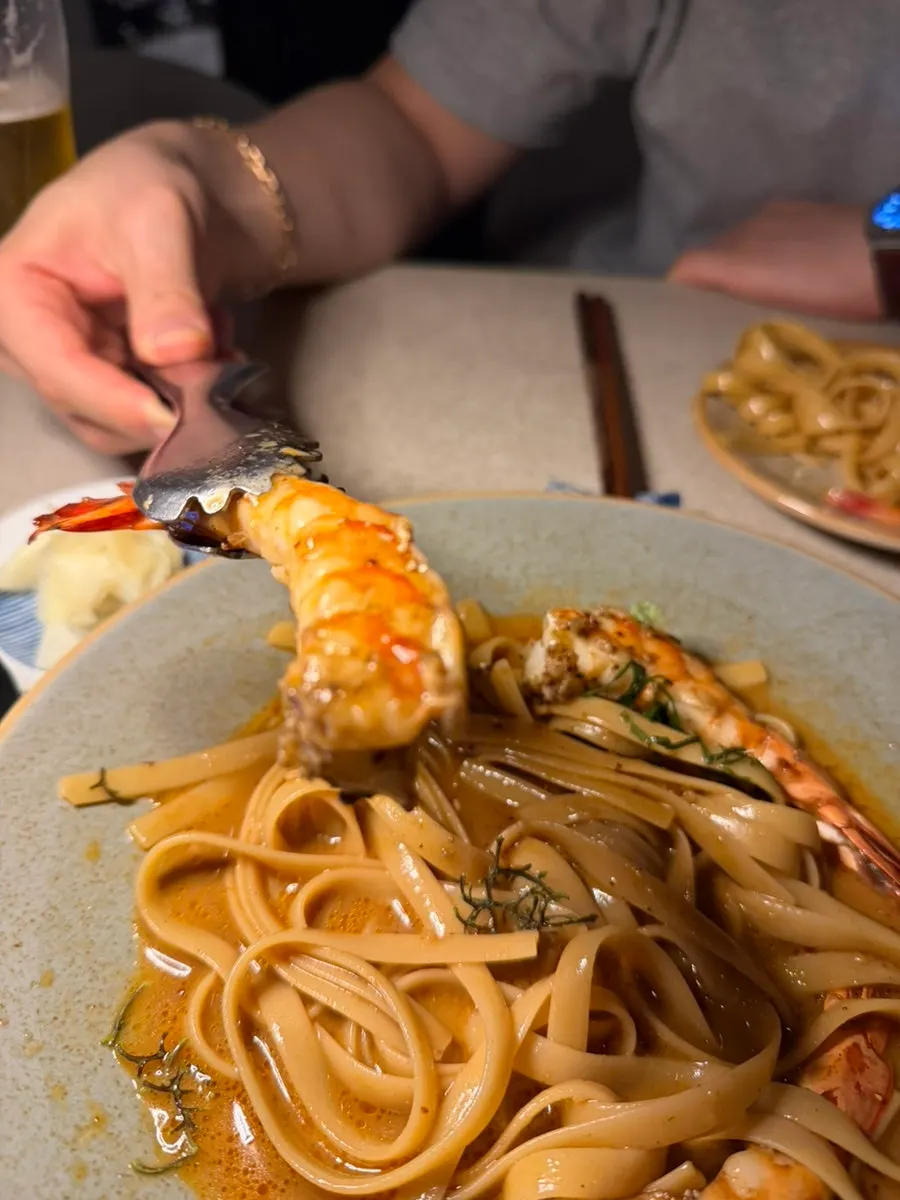 A whole black tiger shrimp on top of the pasta