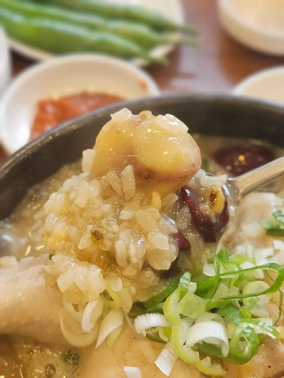 A spoonful of samgyetang broth lifted from the bowl