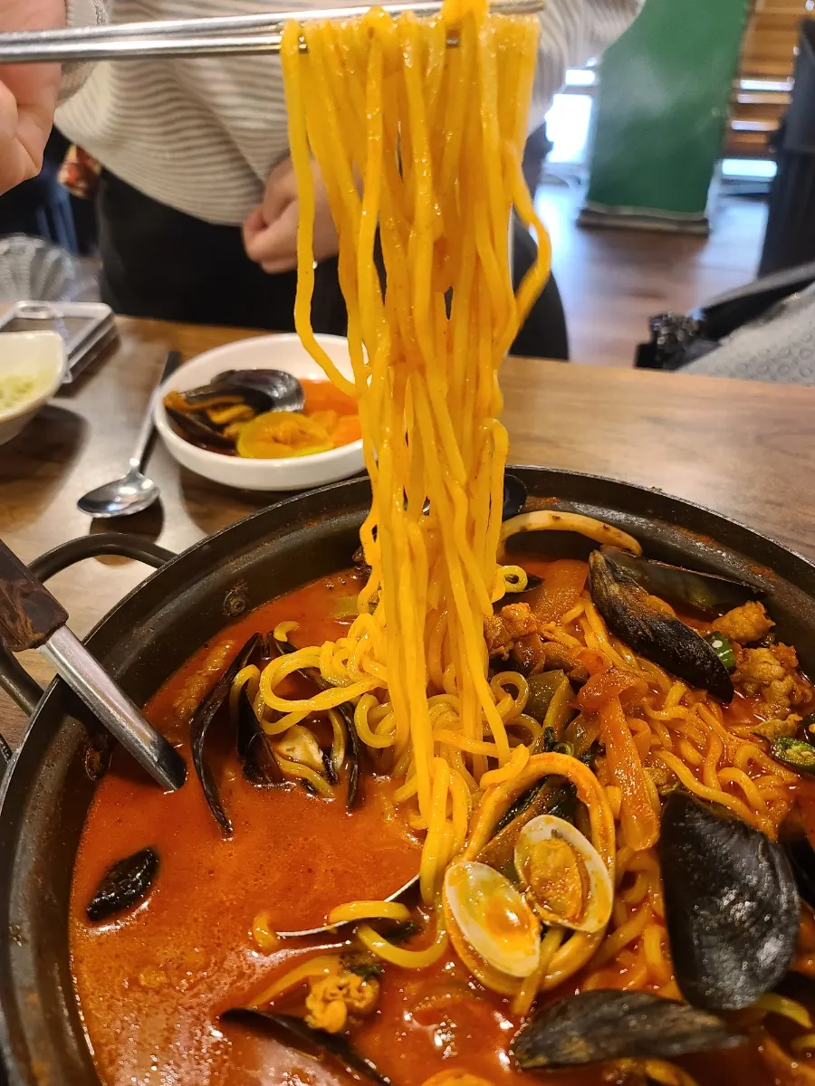 Chewy jjamppong noodles lifted up with chopsticks