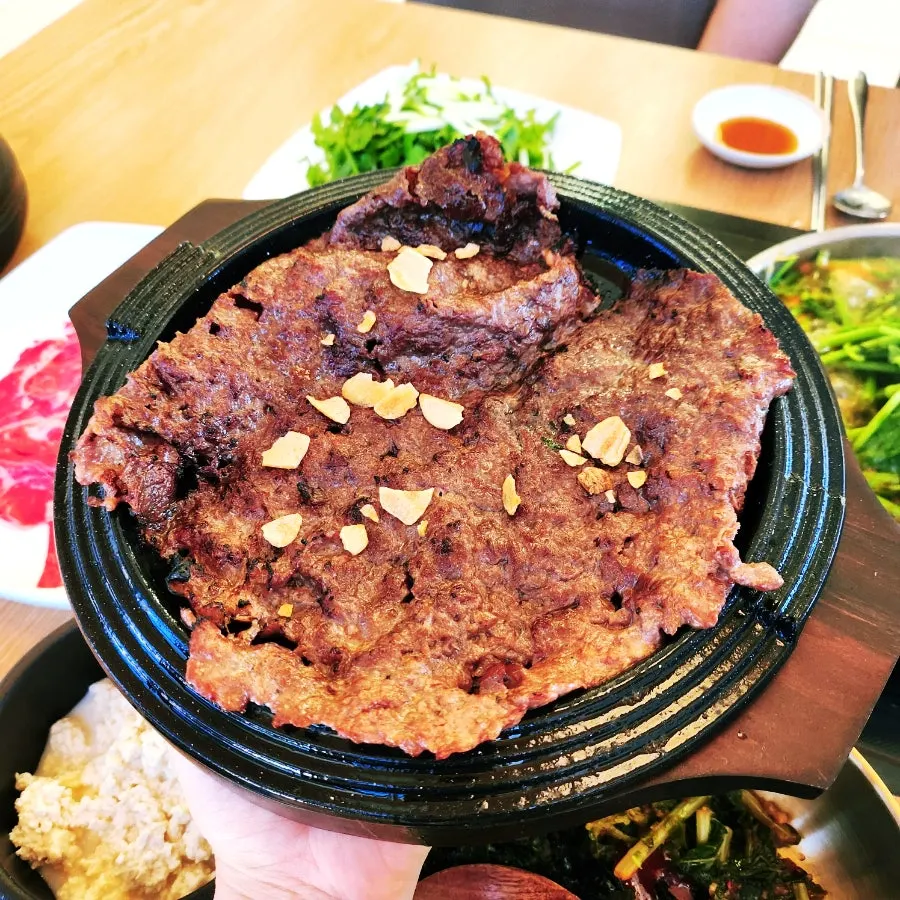 Hot pot of sundubu shabu kalguksu piled with minari and mushrooms