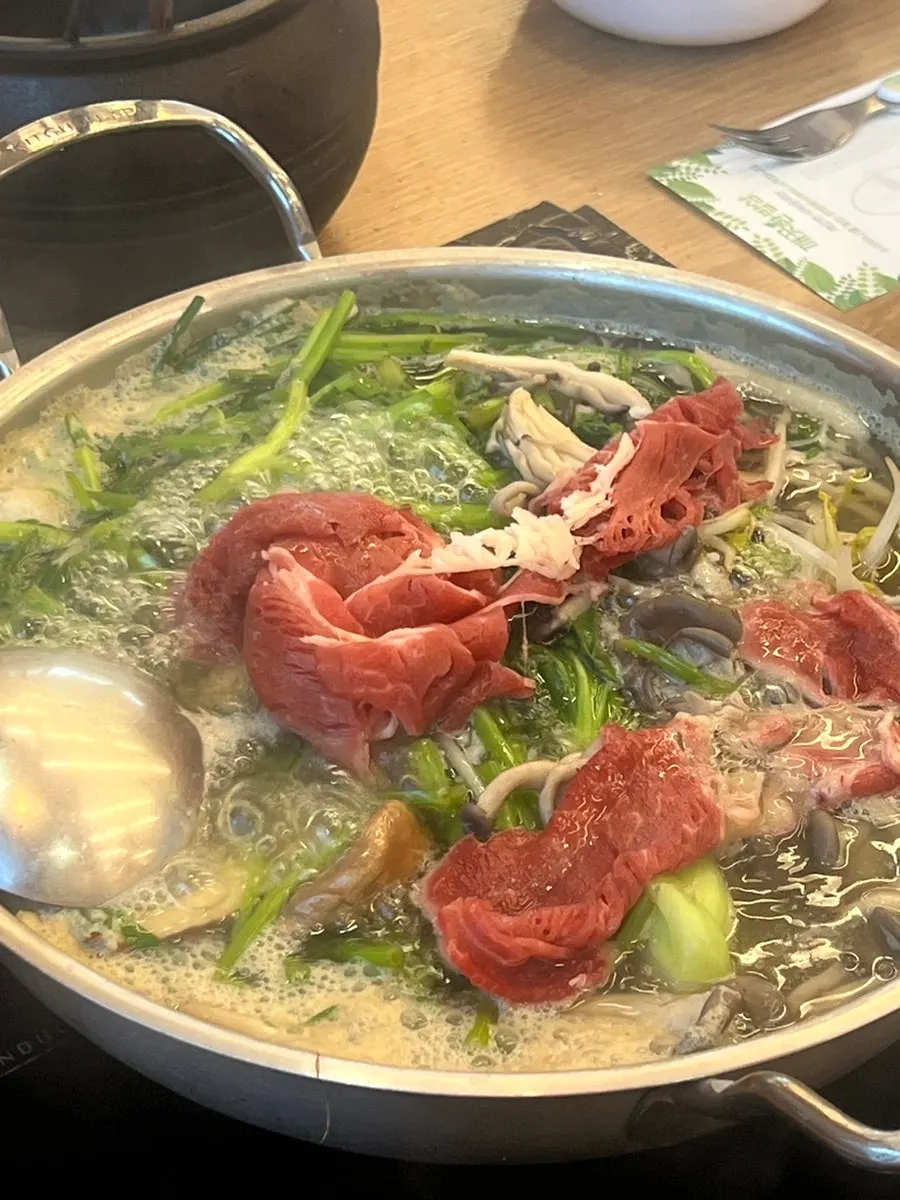 Pot of shabu shabu simmering with vegetables and mushrooms