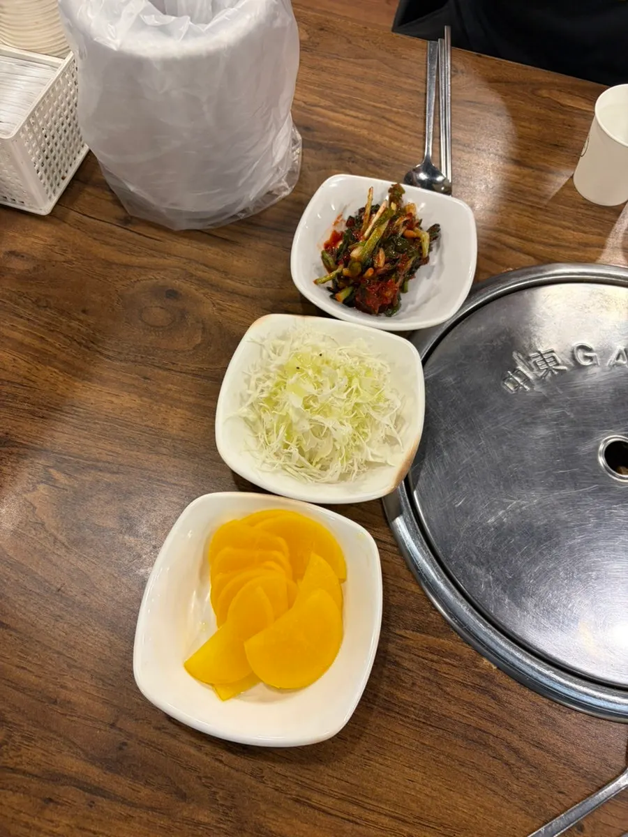 Three side dishes: cabbage salad, pickled radish, and green onion kimchi