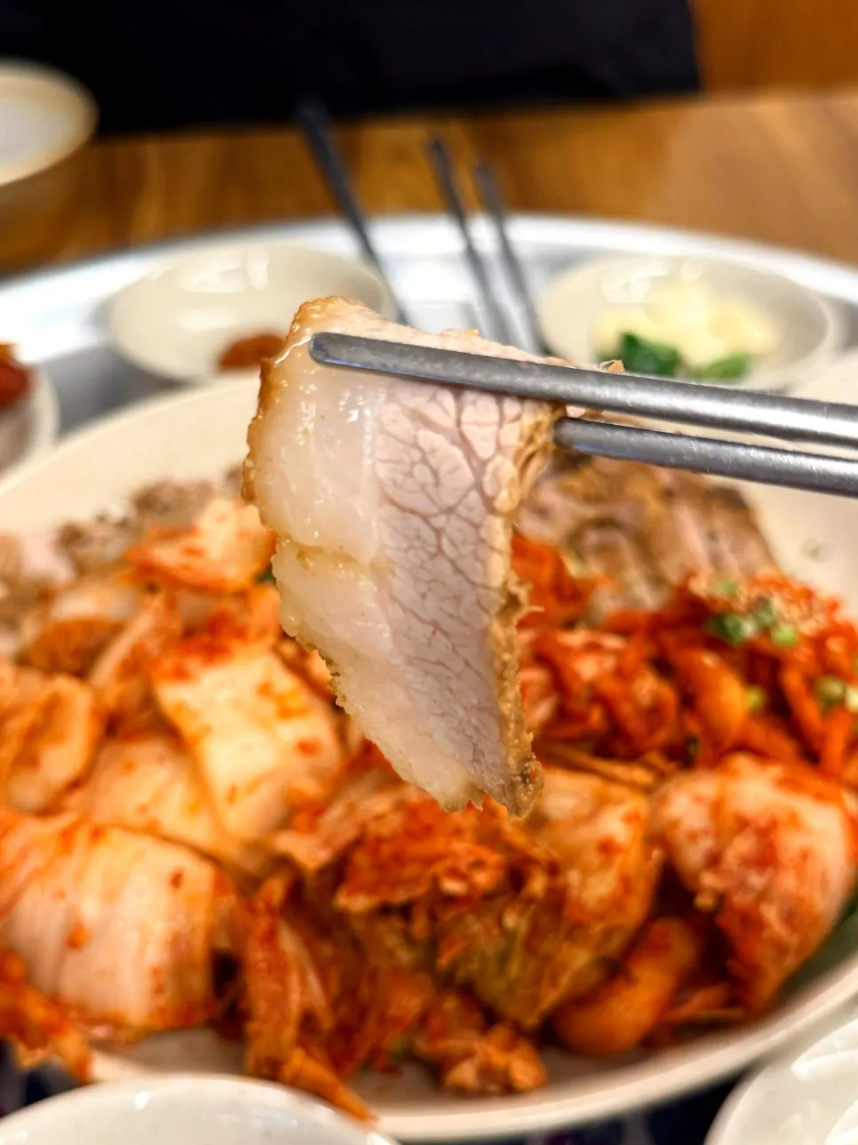 A piece of bossam topped with radish salad and bossam kimchi