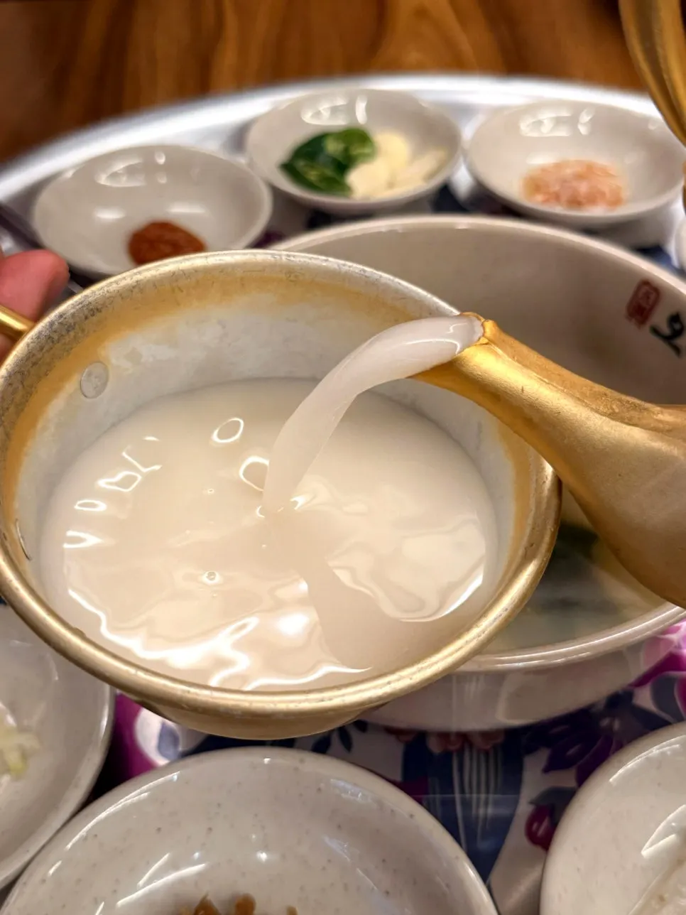 A glass of Jipyeong Makgeolli with bossam as a side dish