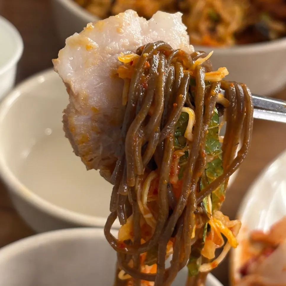 A piece of bossam topped with bossam kimchi and garlic
