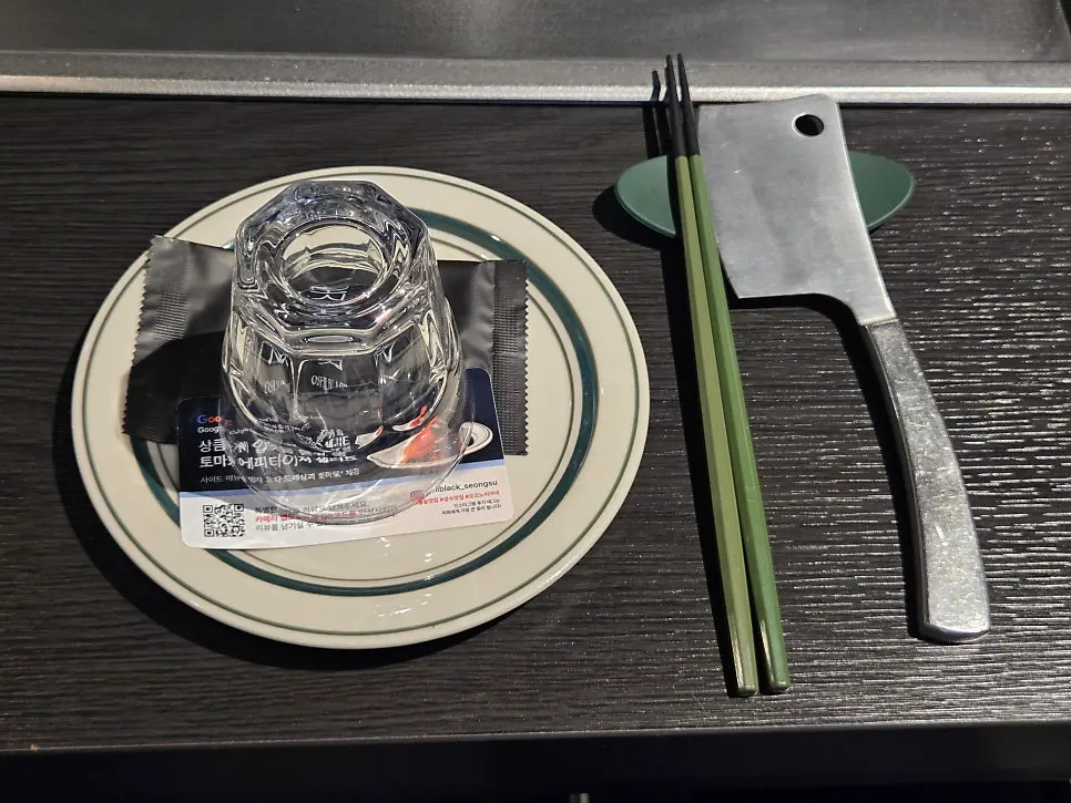 Basic table setting with water cup, small plate, chopsticks, and mini hatchet-shaped tool