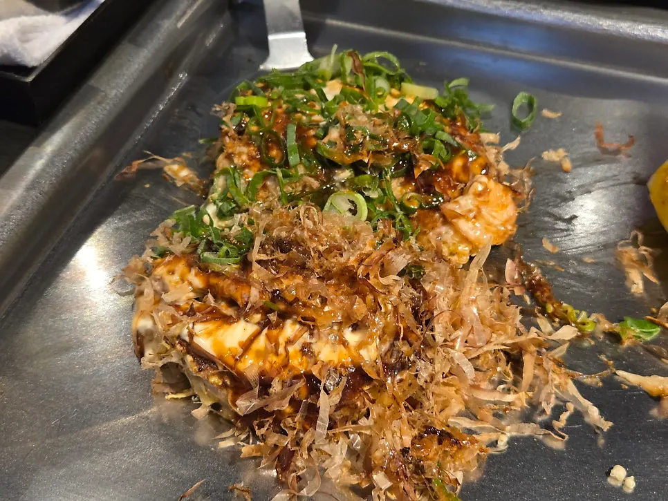 Okonomiyaki topped half with bonito flakes and half with green onion