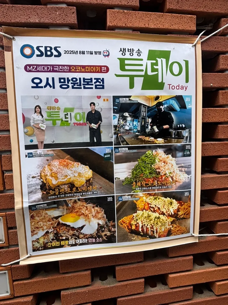 Oshi Black signboard in front of a red brick building