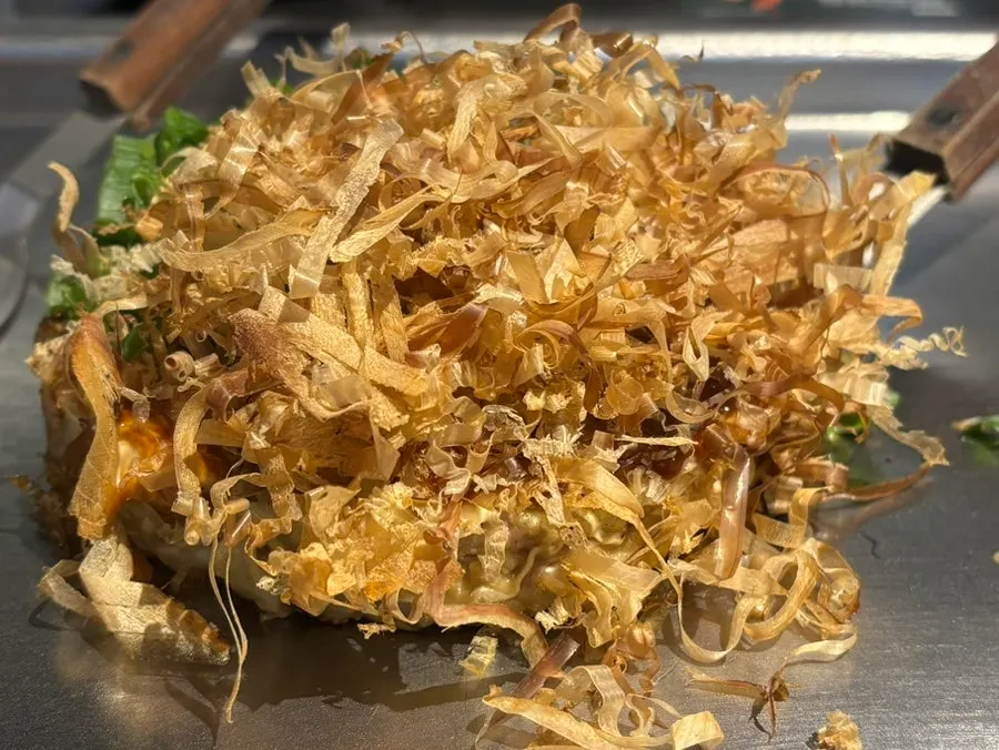 Okonomiyaki topped generously with bonito flakes