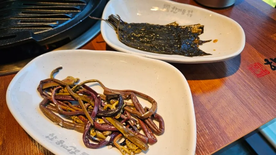 Plates of cabbage kimchi salad and perilla leaf pickles