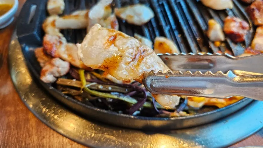 A piece of pork jowl dipped in sesame oil sauce