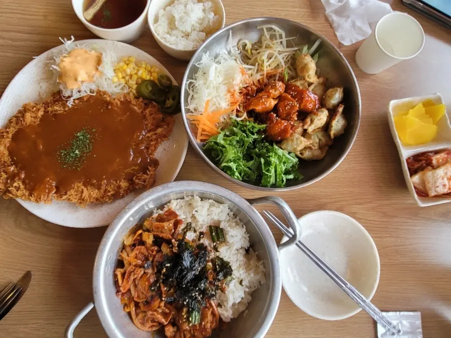 Full spread of spicy pork rice bowl, old-style pork cutlet, and bibim mandu