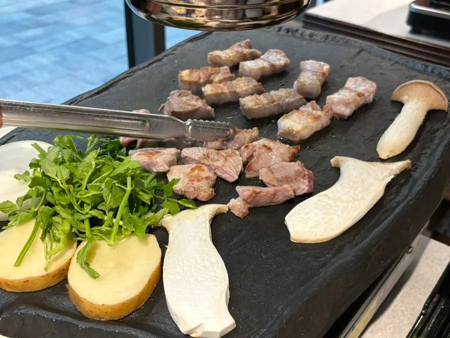 Meat grilling on the stone plate with onions and mushrooms