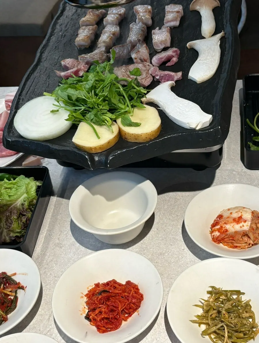 Black pork samgyeopsal sizzling on the grill
