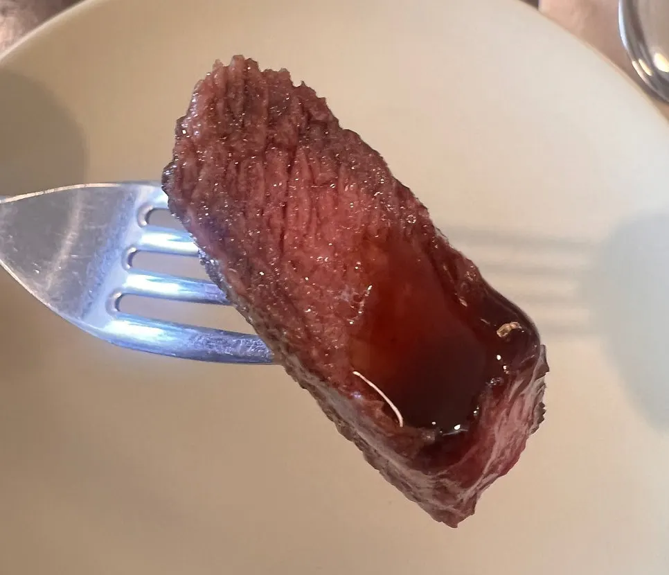 A piece of steak with sauce and wasabi