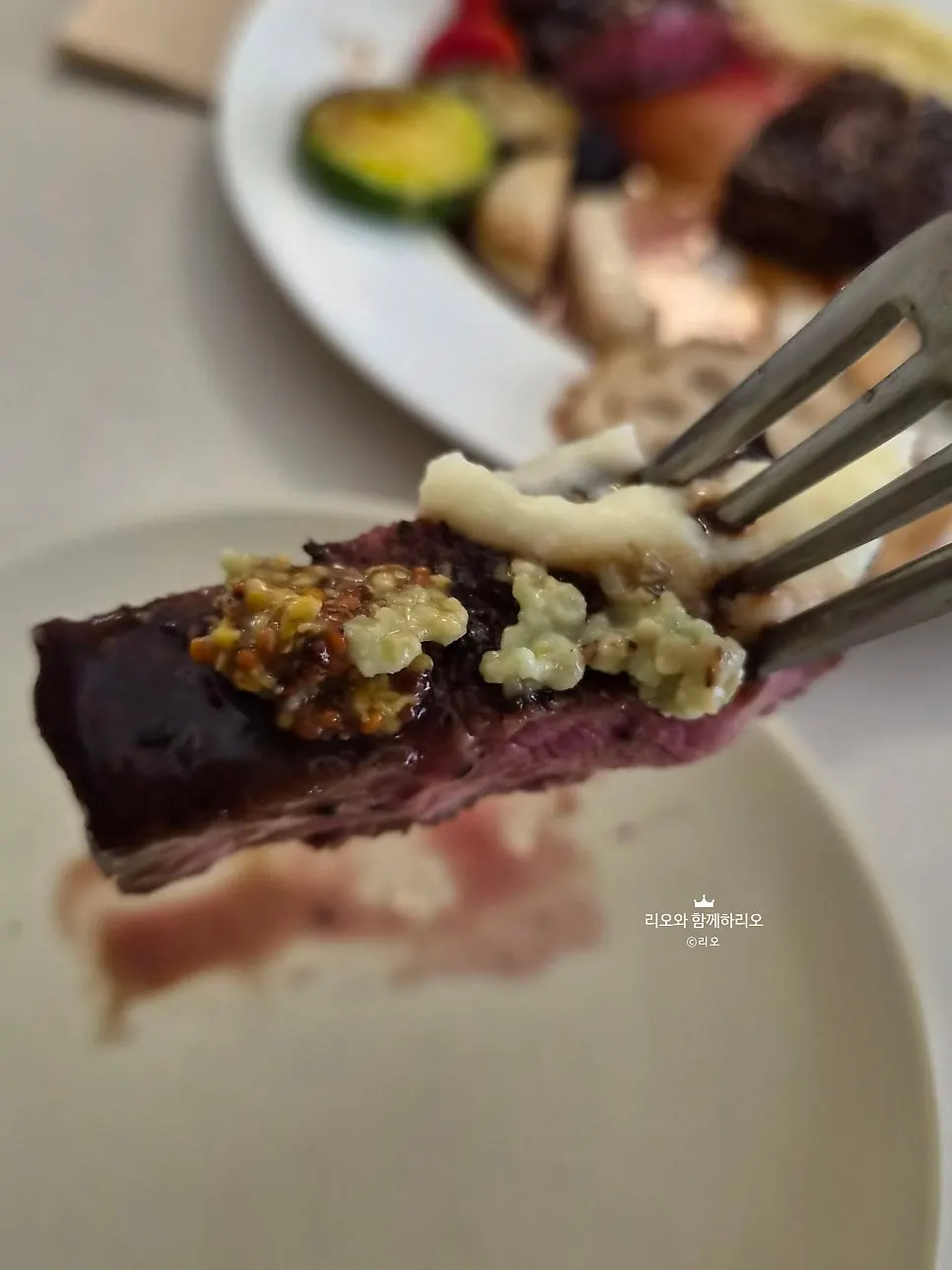 A bite of steak paired with grain mustard and wasabi sauce