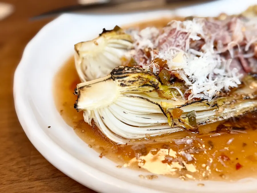 Grilled baby cabbage salad topped with bacon and cheese