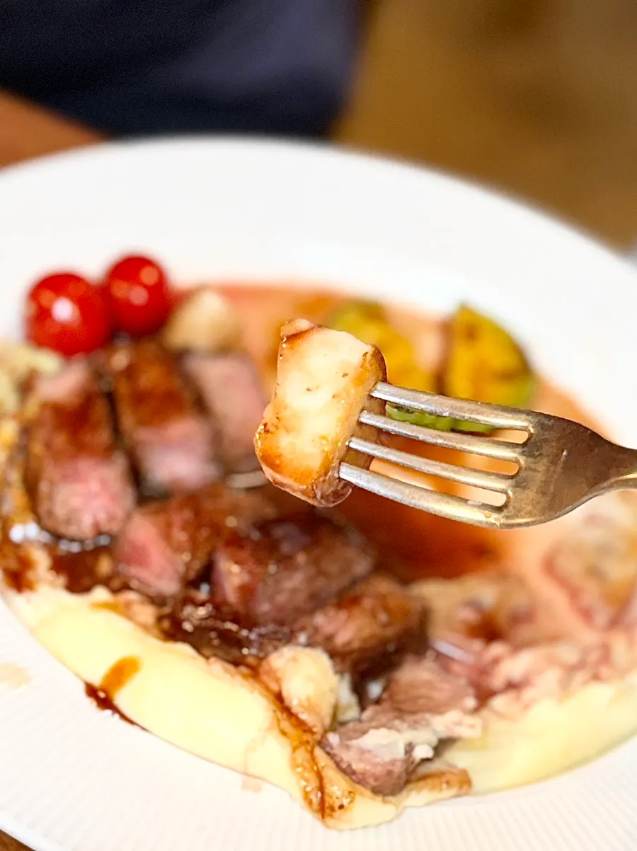 A piece of steak served with mashed potatoes
