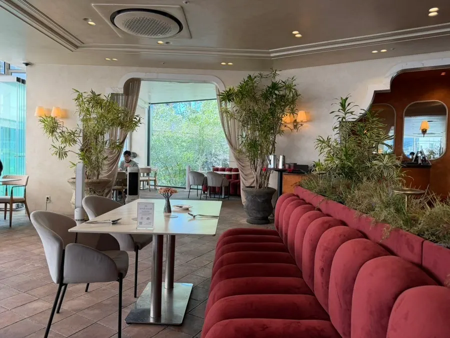 Seating with deep red velvet sofas and marble tables
