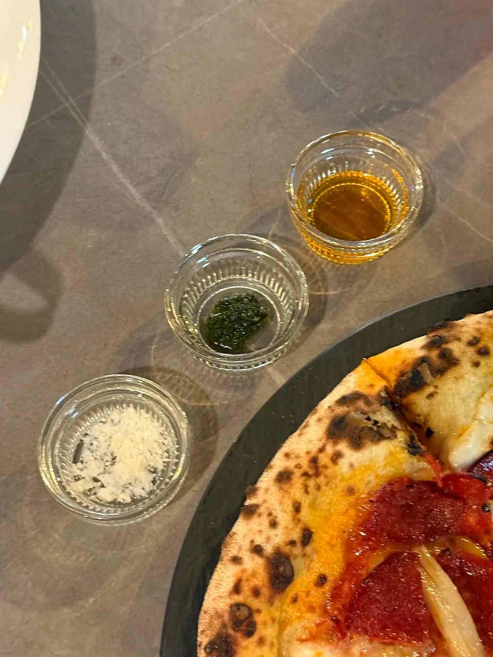 Reggiano cheese and basil sauce served alongside the pizza