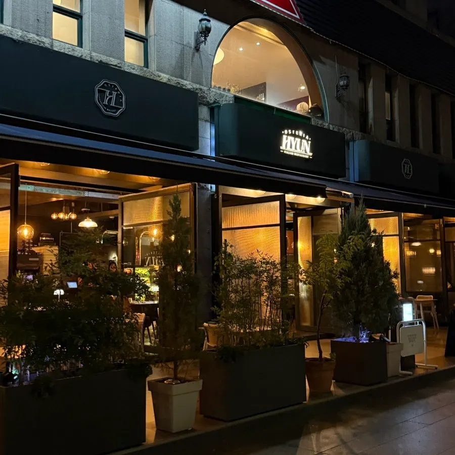 Osteria Hyeon's exterior and terrace seating lit with orange lighting