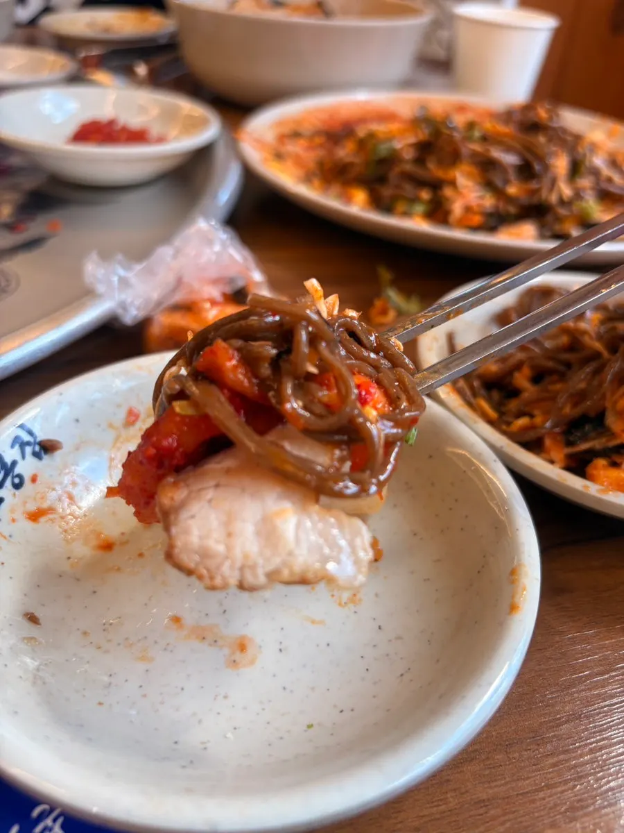 Jaengban makguksu topped with sauce and vegetables