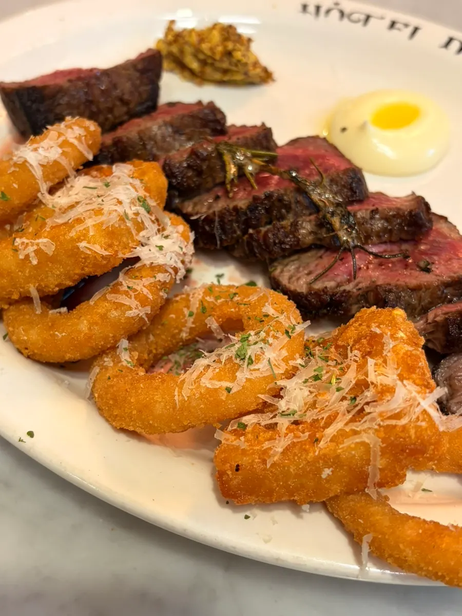Steak served with onion ring and potato garnish