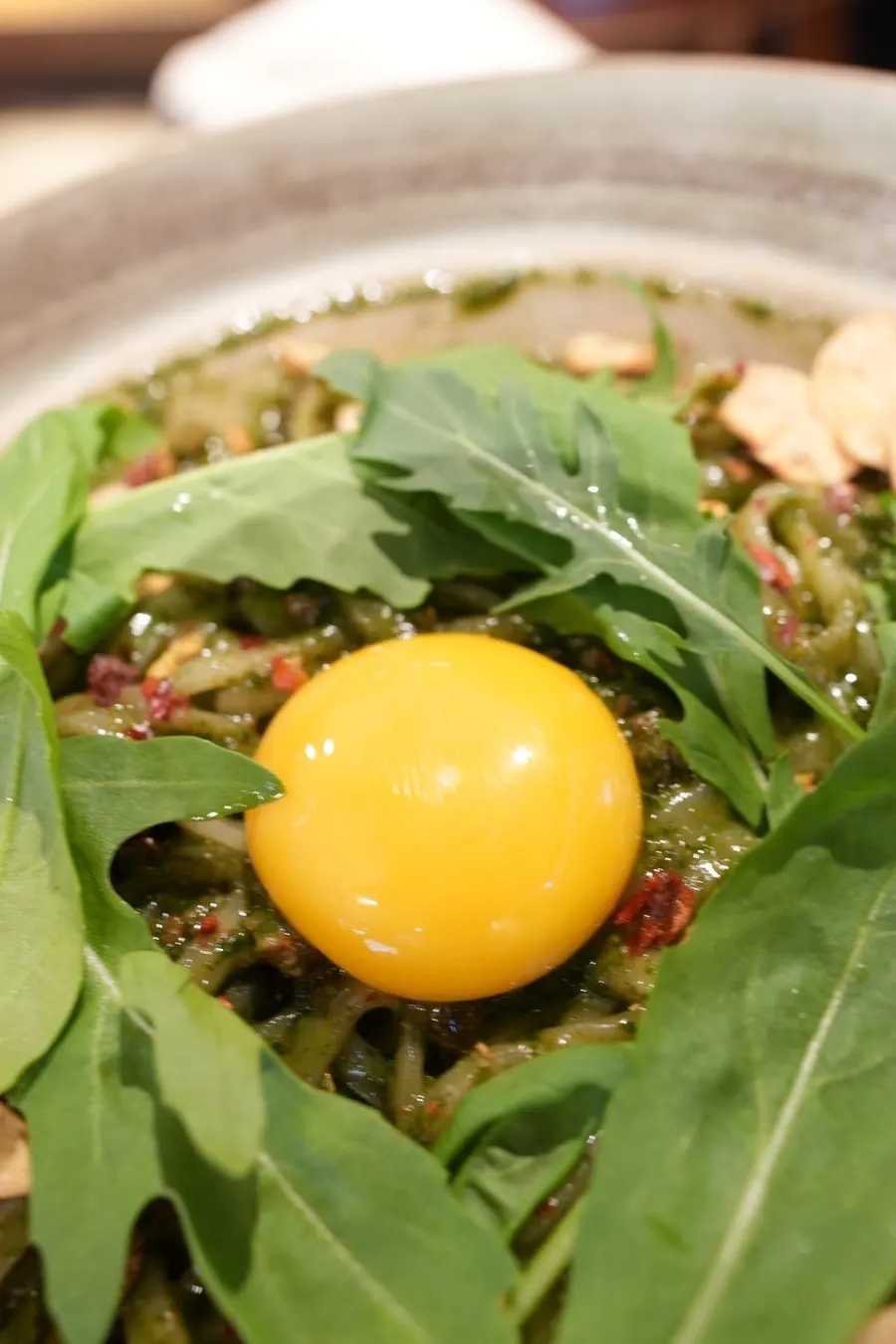 Egg yolk placed on basil pesto noodles