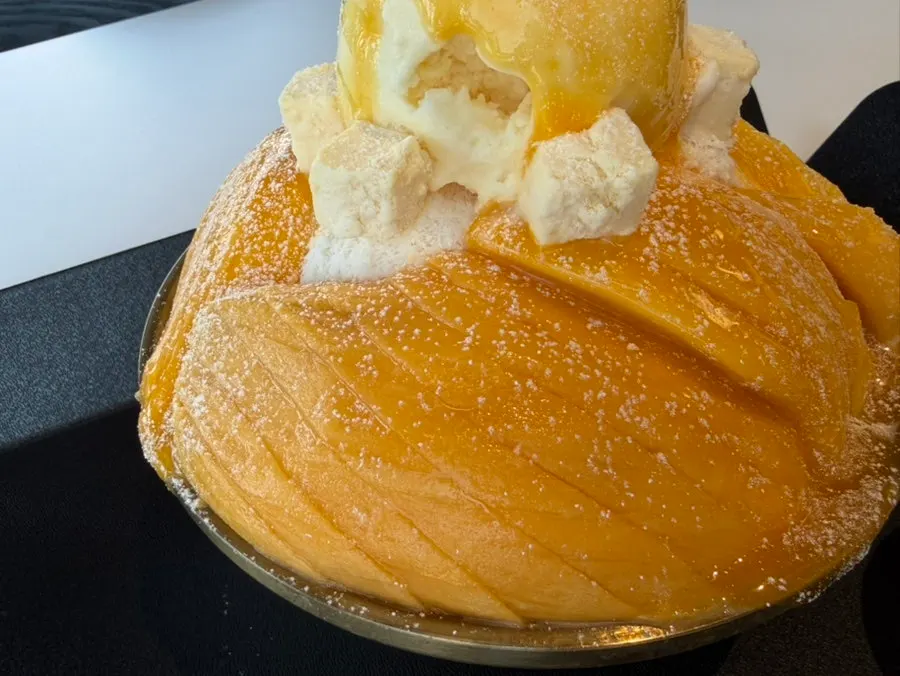 Bowl of mango bingsu with a side of mango syrup