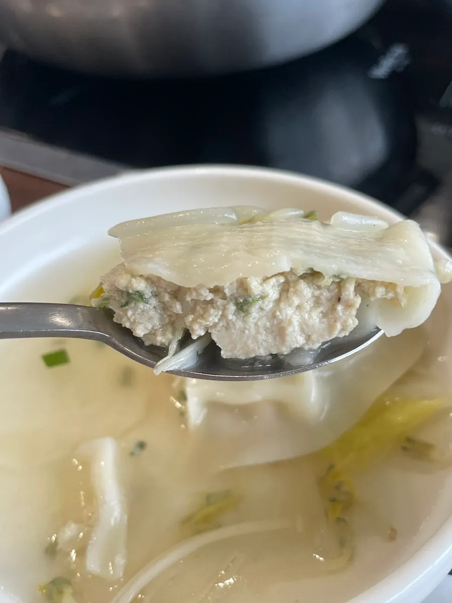 Large handmade Pyeongyang dumpling cut with a spoon