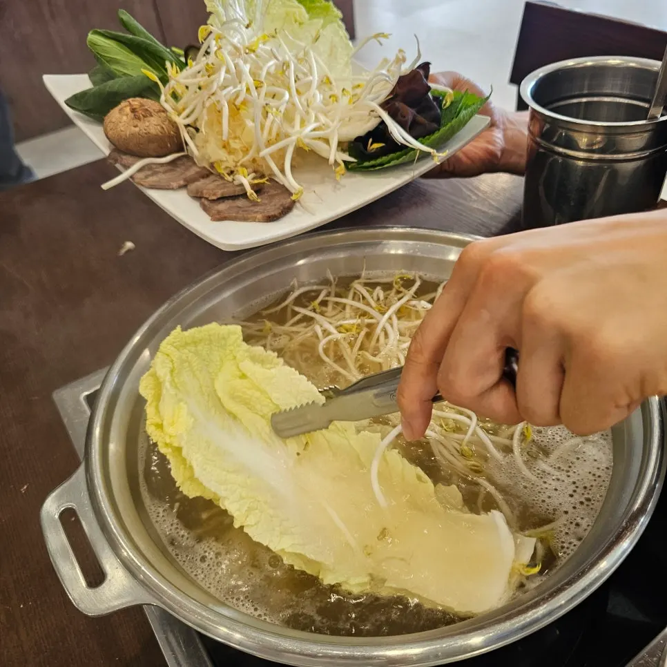 煮立ったスープに具材を入れるマンドゥ鍋