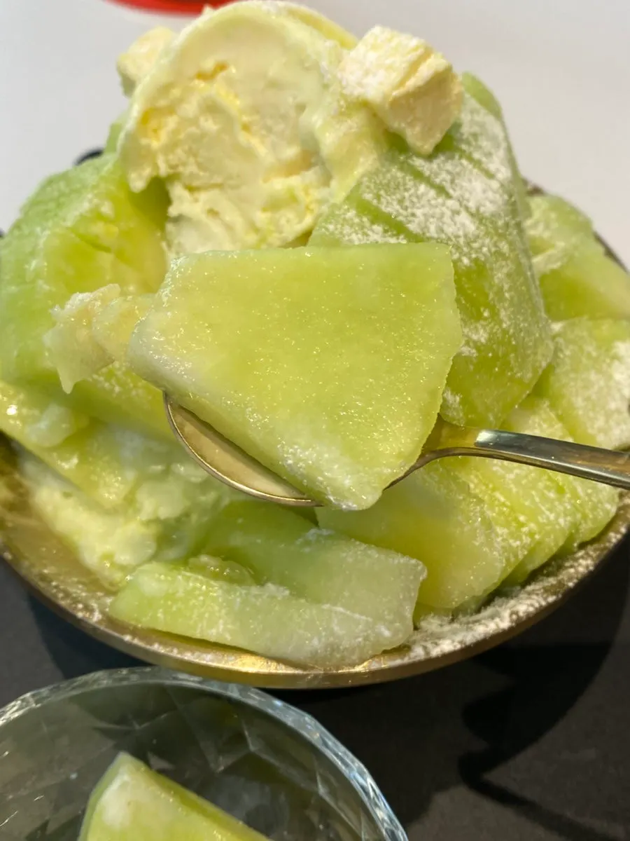 Snow bingsu topped with melon, cheese cubes, and yogurt ice cream