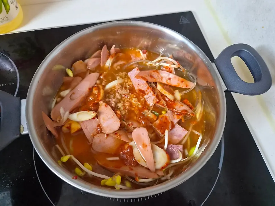 Uncooked budae jjigae ingredients and broth packed for takeout