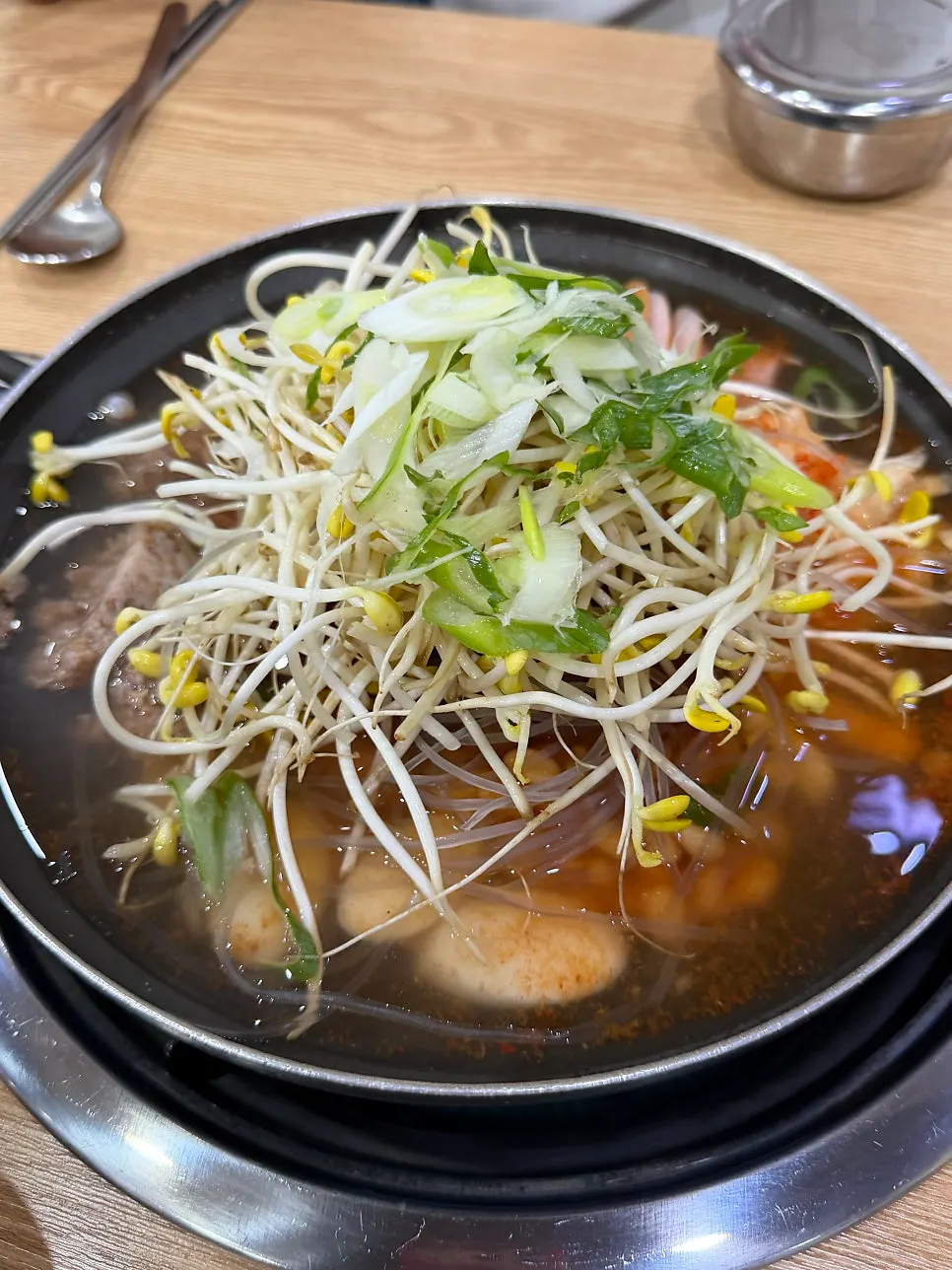 Budae jjigae topped with ham, rice cake, and bean sprouts
