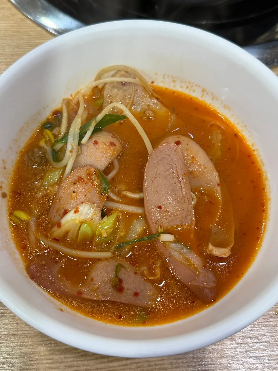 A ladleful of budae jjigae packed with ingredients
