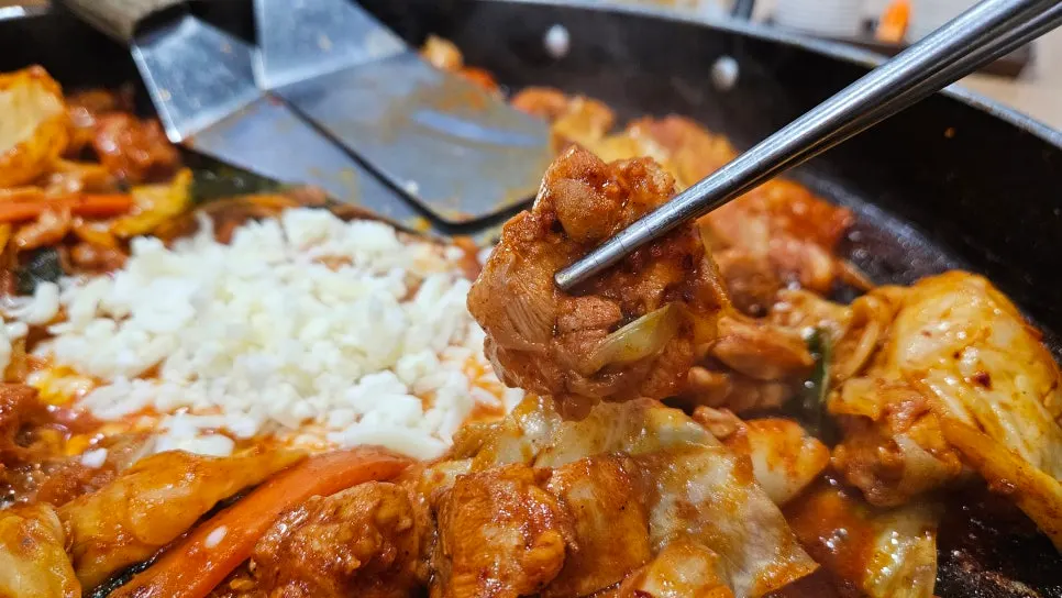 치즈가 덮인 매콤한 철판 치즈닭갈비