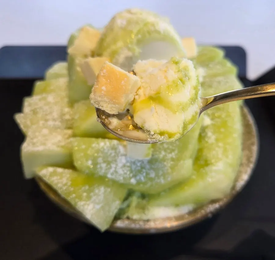A spoonful combining vanilla ice cream and cheesecake with the bingsu
