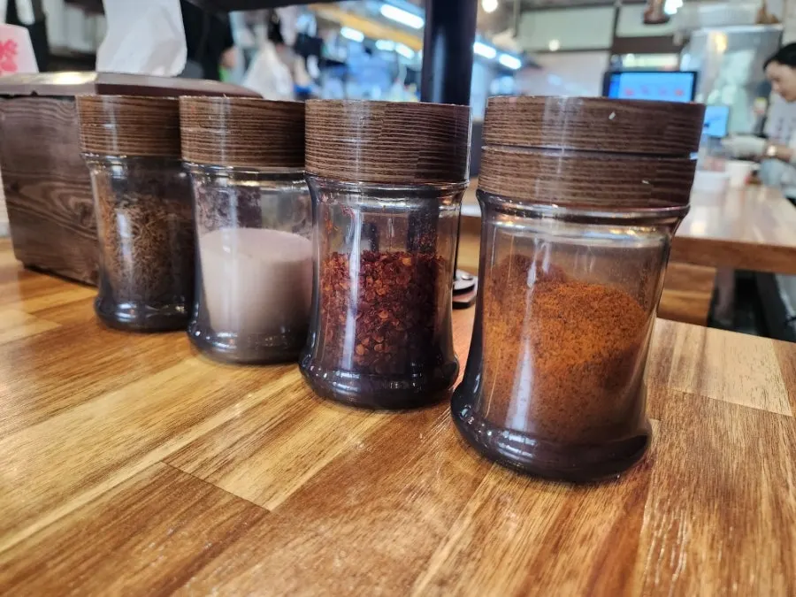 Dipping a lamb skewer into cumin seasoning