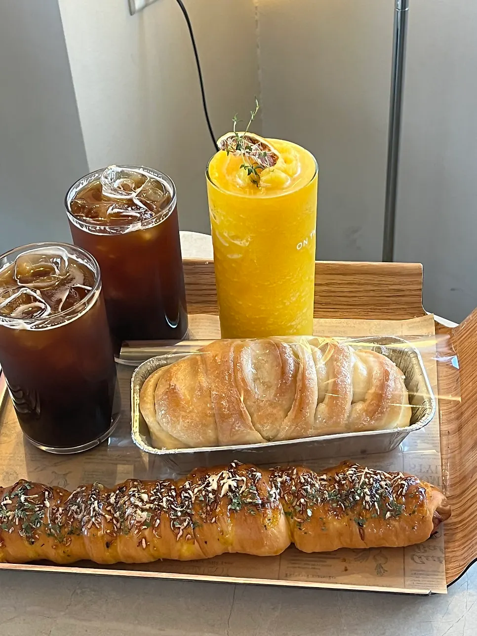 Table with long sausage bread, condensed milk bread, and hallabong smoothie