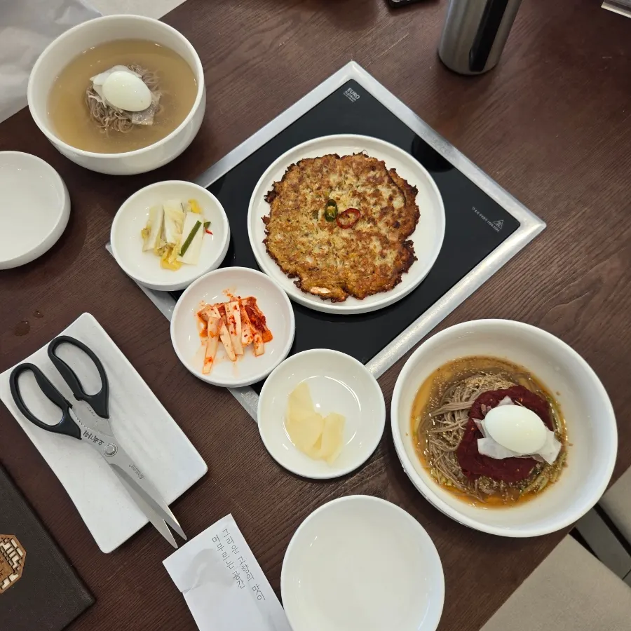 Table spread with Pyeongyang water makguksu, bibim makguksu, and mung bean pancake