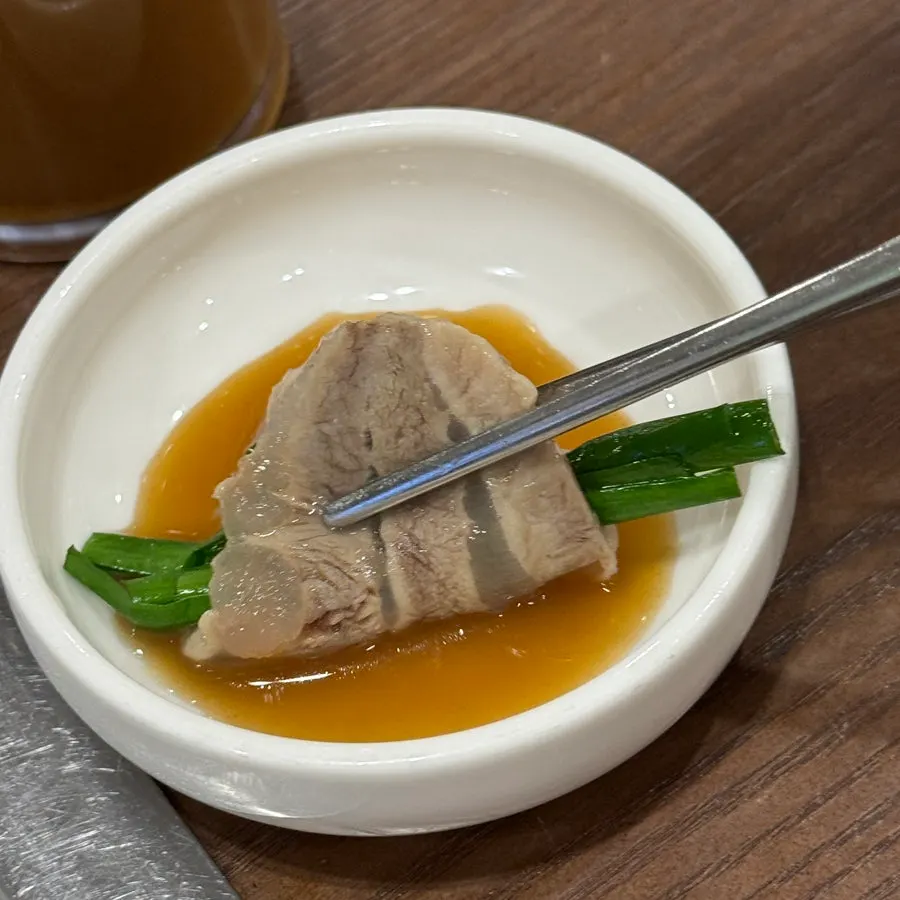 Dipping arongsatae suyuk into the tangy sauce