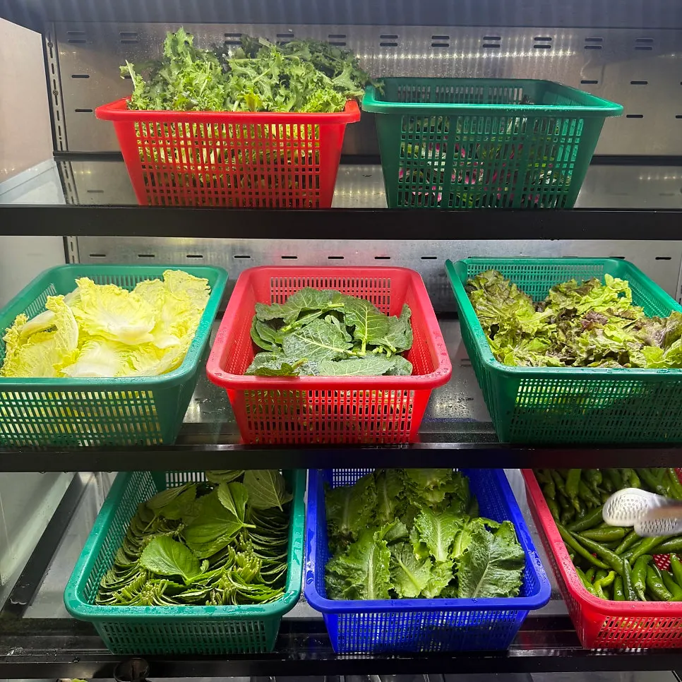 A full table with namul, salad, and wrap vegetables