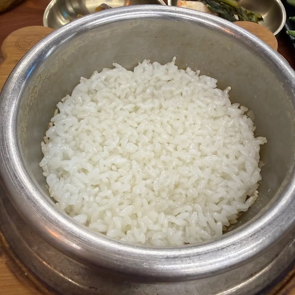 A wrap green topped with rice, pork, and gangdoenjang
