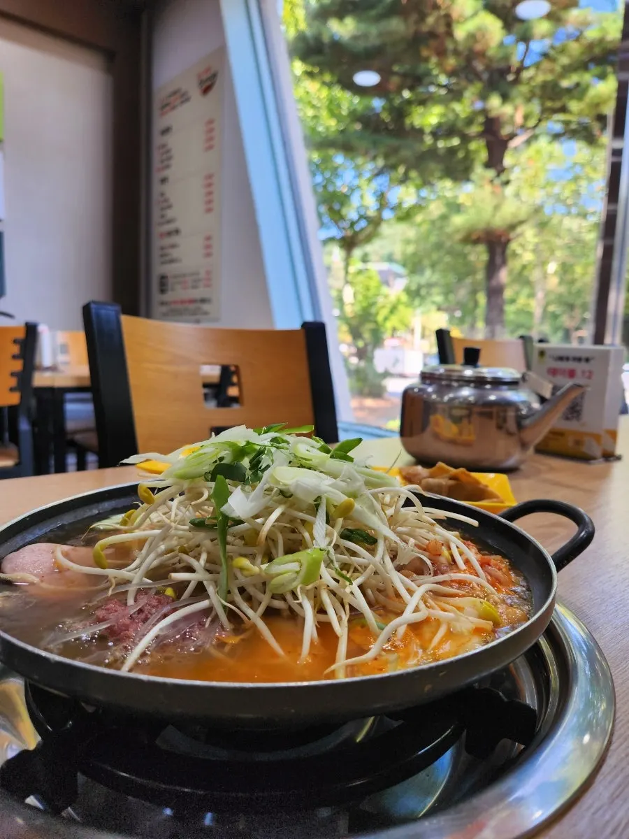 Budae jjigae boiling with ramen noodles added