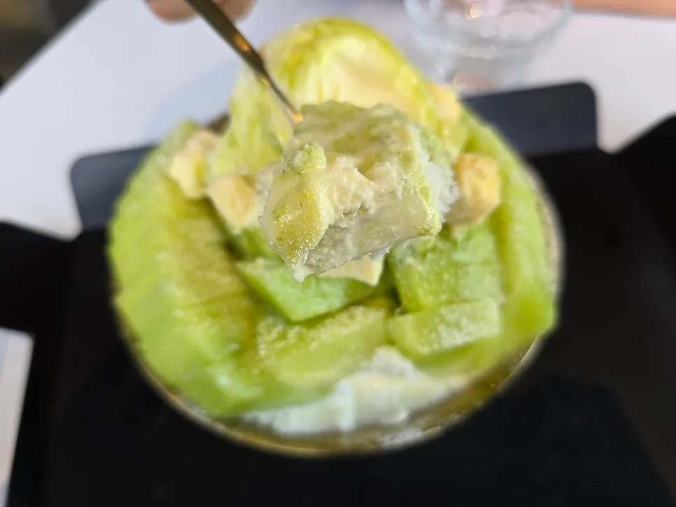 Melon bingsu portioned into a glass bowl