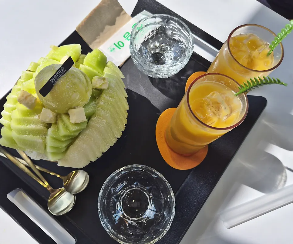 Table set with melon snow bingsu and fresh mango juice