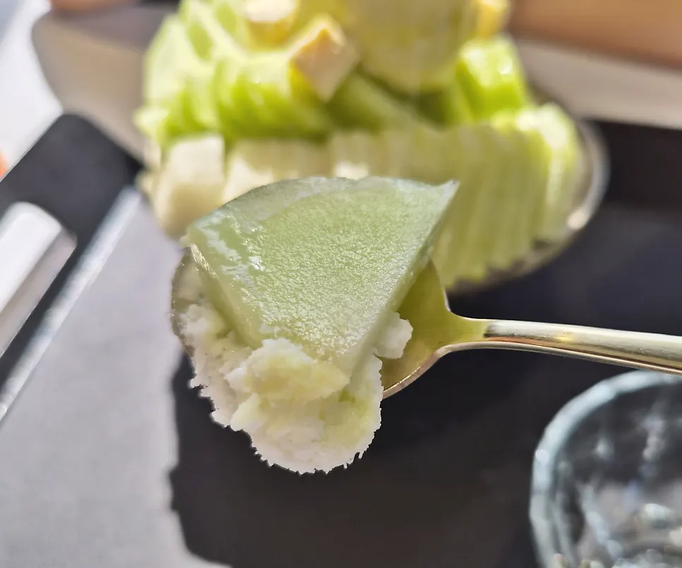 Melon bingsu with the cheese topping partially eaten